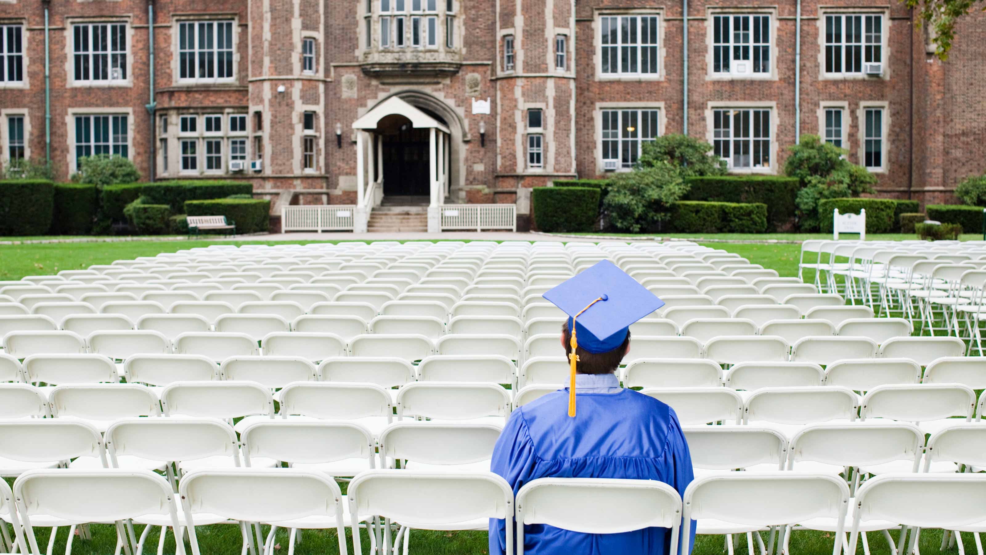 Un étudiant est assis en casquette et en robe, prêt à obtenir son diplôme.