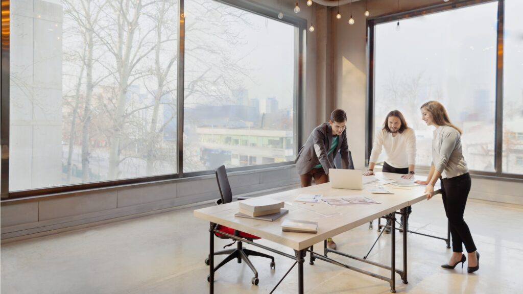 Three businesspeople gather around a temporary table in a new workspace.