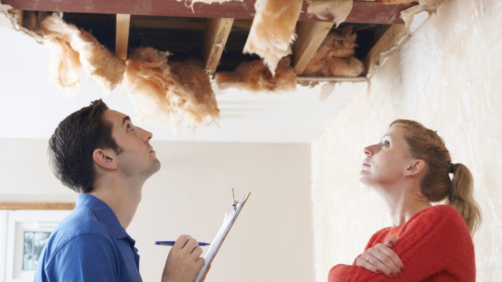 An insurance claims adjuster and a homeowner check out a damaged ceiling.