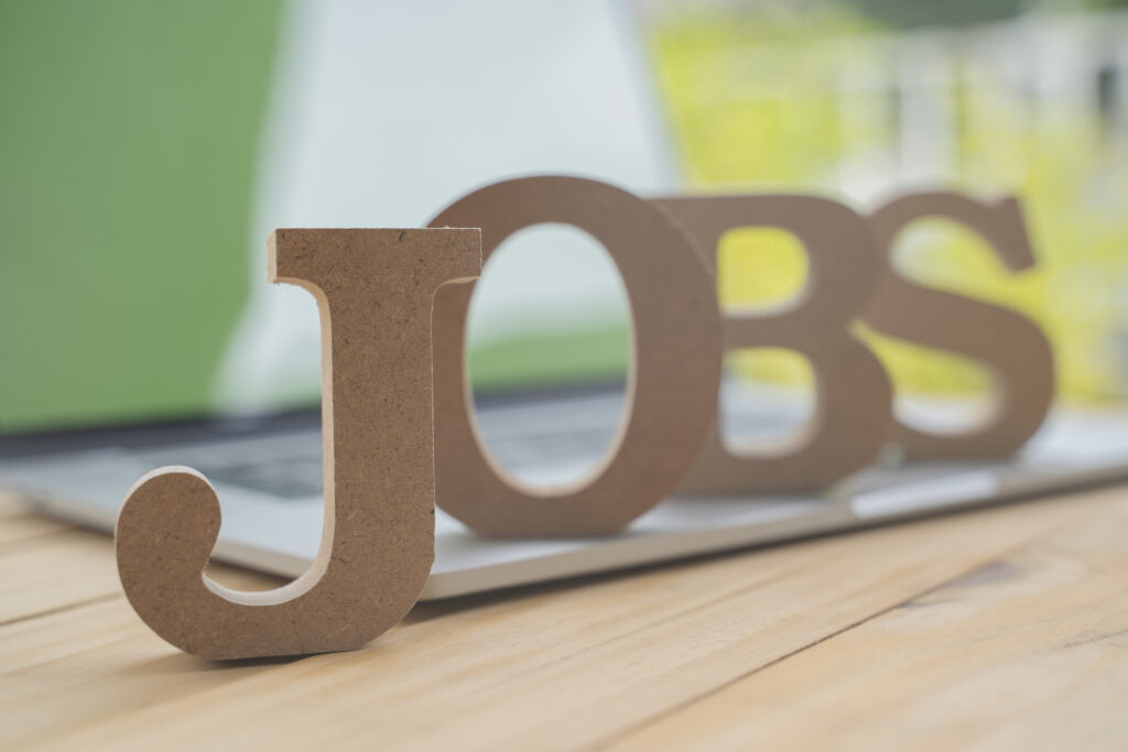 The word "jobs" written in wooden letters that are placed on top of a laptop keyboard