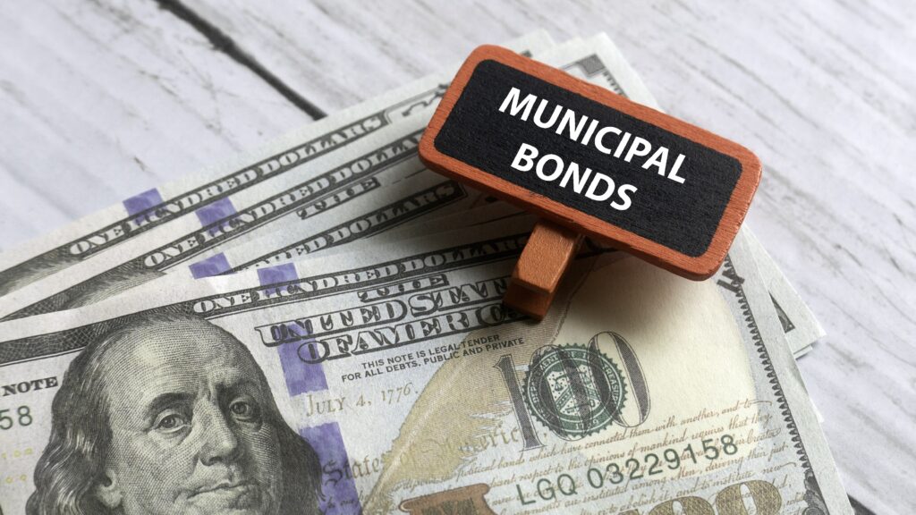 A clip that says municipal bonds sits atop fanned-out hundred-dollar bills.