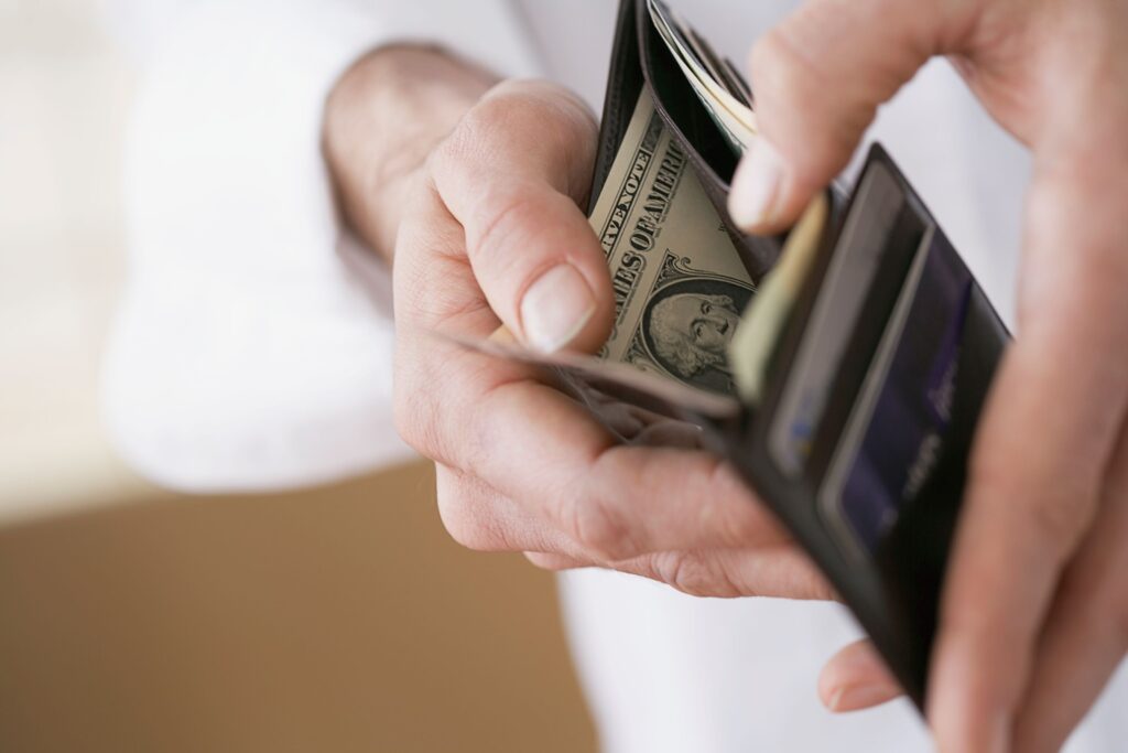 A man reaches into his wallet to take out money.