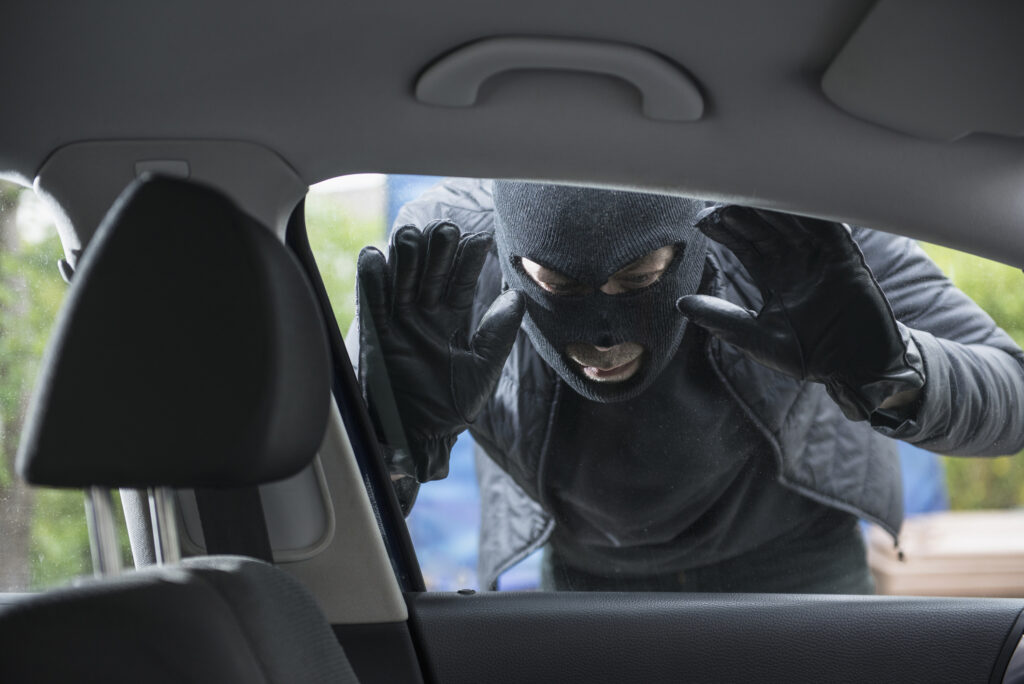 Thief is looking in the window of a car.