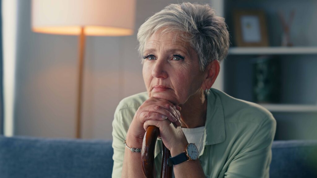 An older woman rests her chin on her hands as she thinks about something serious.