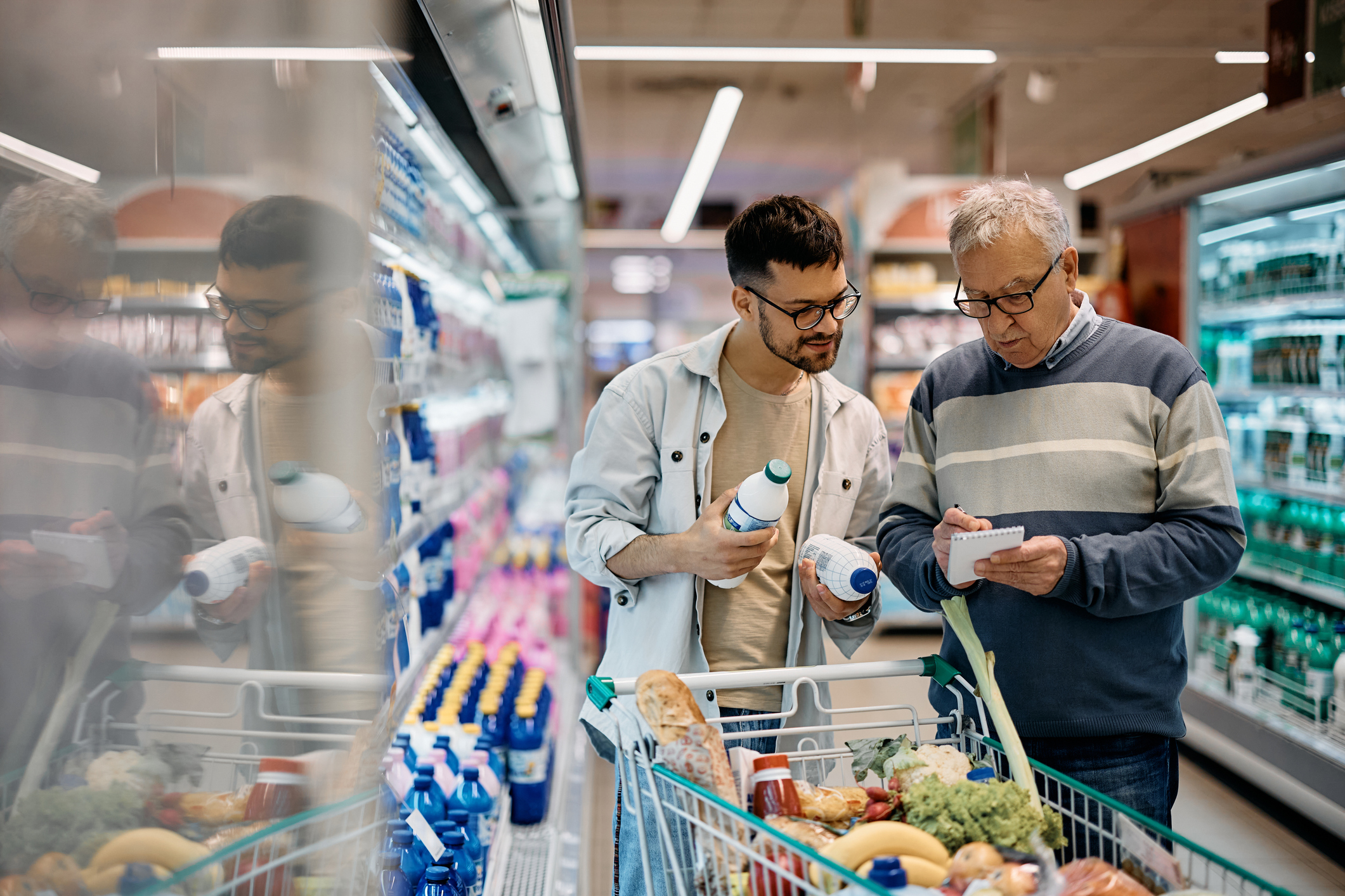Young Man et son père senior passent par la liste des courses tout en achetant au supermarché