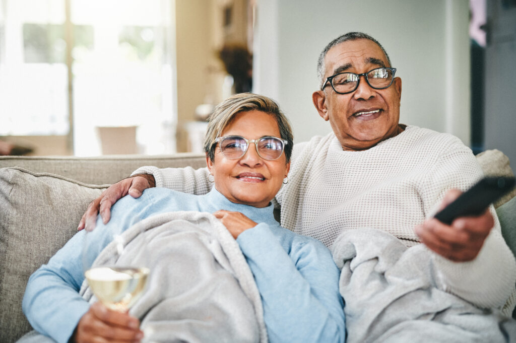 A senior couple watches streaming services while relaxing on the couch.