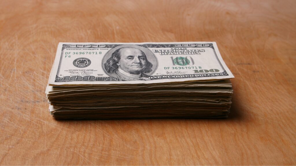 A stack of hundred-dollar bills on a table.