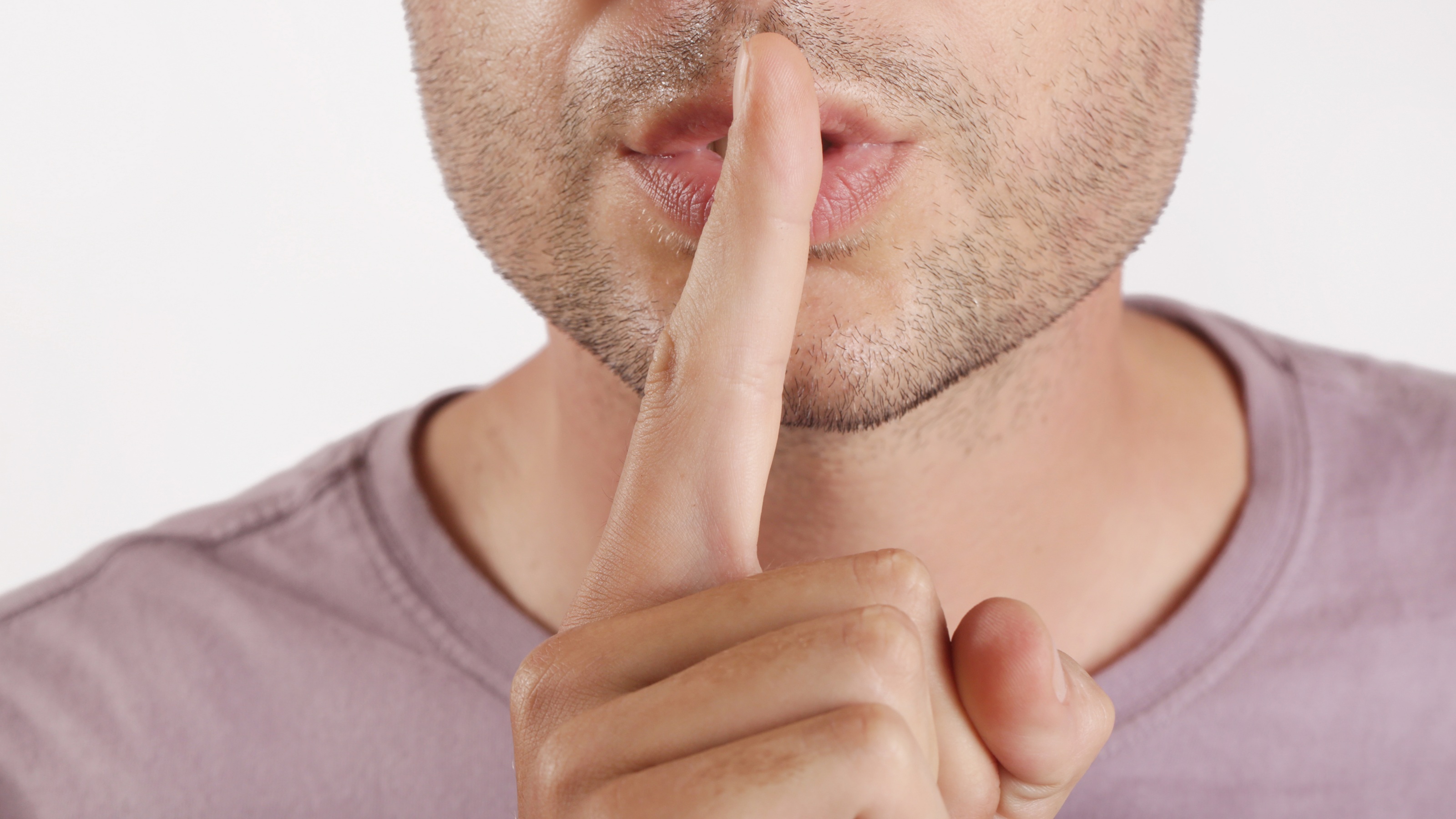 Un homme met son doigt sur ses lèvres comme pour dire, 