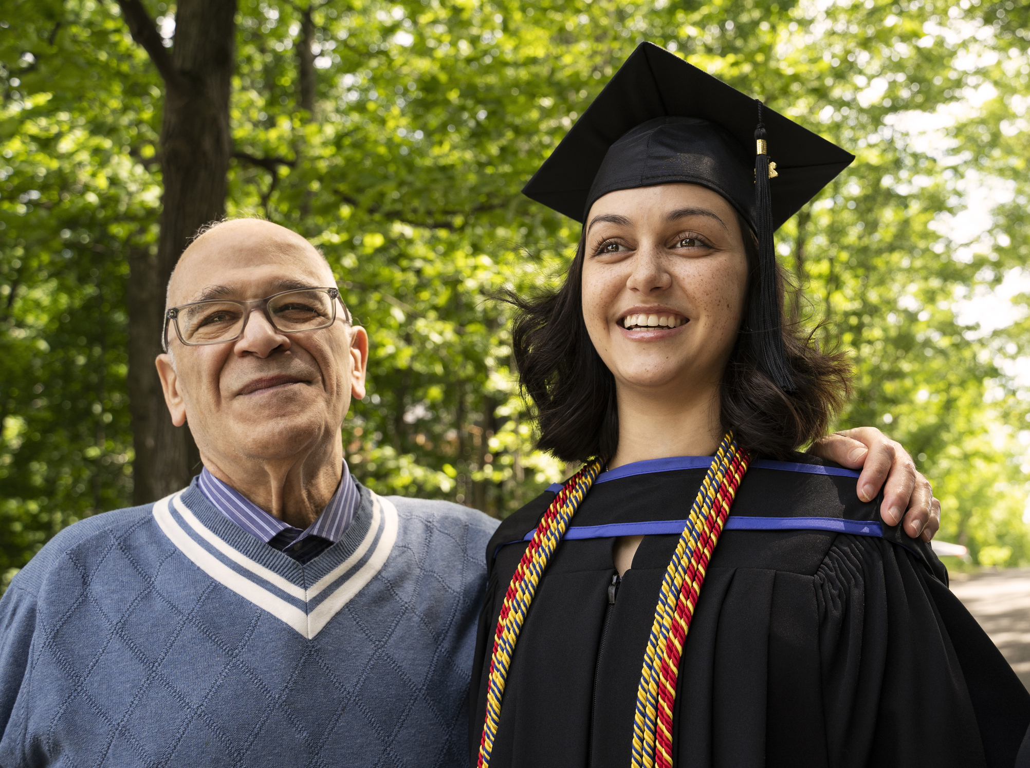 Proud grandfather with his arm around his university graduating granddaughter, portrait.