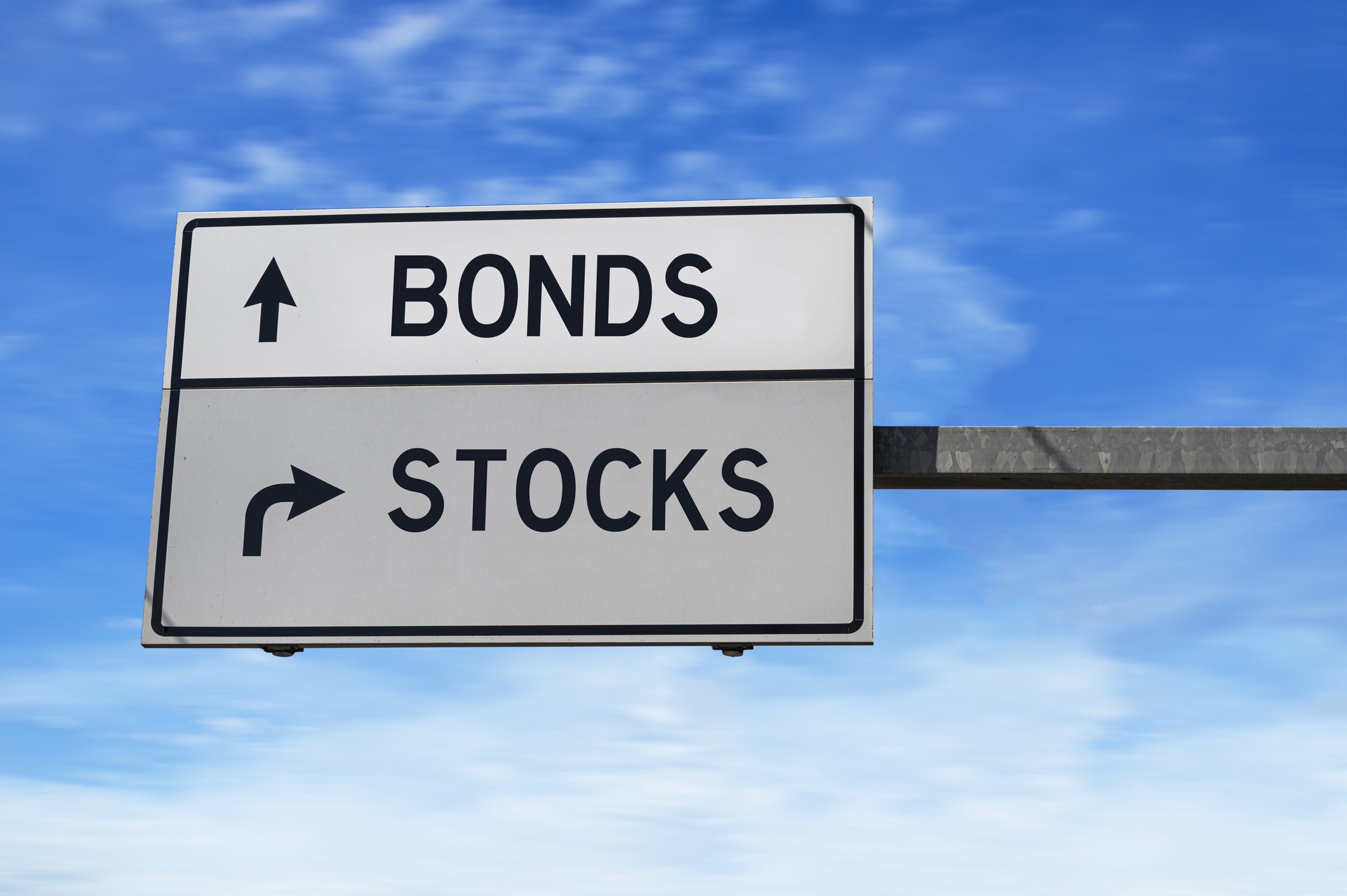 A white road sign with the word bonds next to an arrow pointing straight ahead and the word stocks next to an arrow pointing to the right.