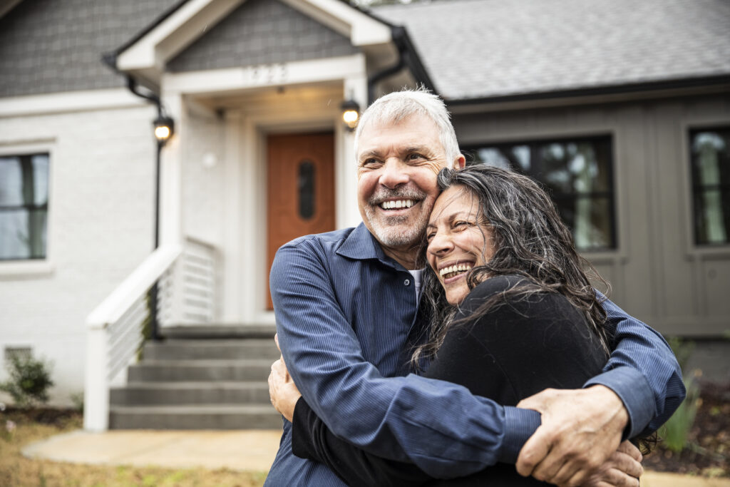 A couple embracing in front of their new home