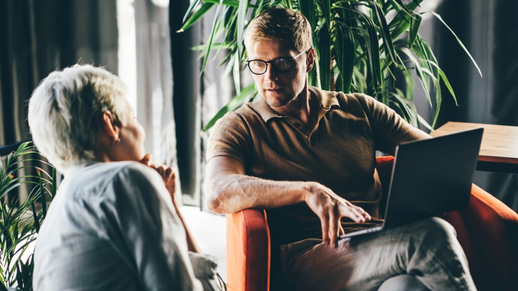 An adviser talks with an older woman in a comfortable office.