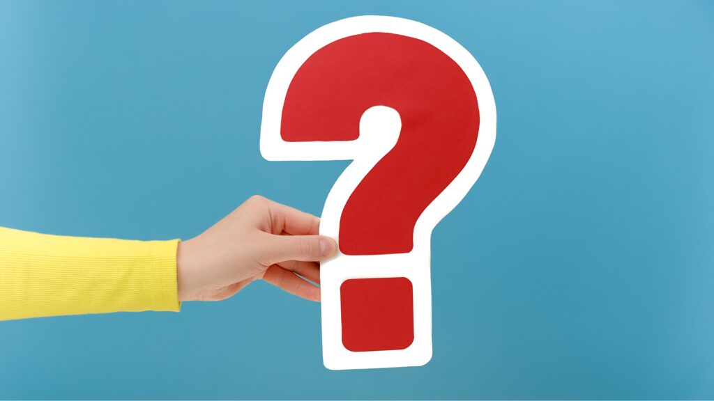 A woman's hand holds a red question mark outlined in white against a blue background.