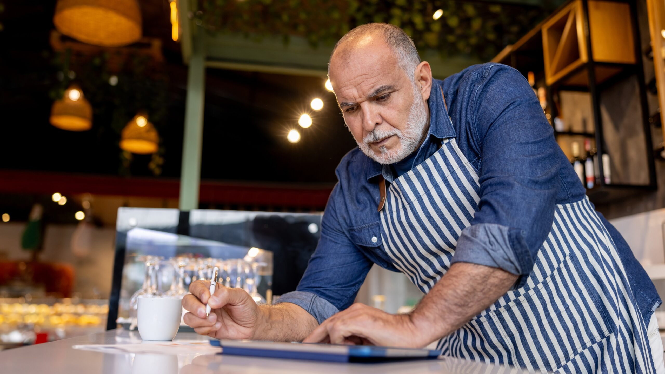 An older business owner looks at his table in his coffee shop.