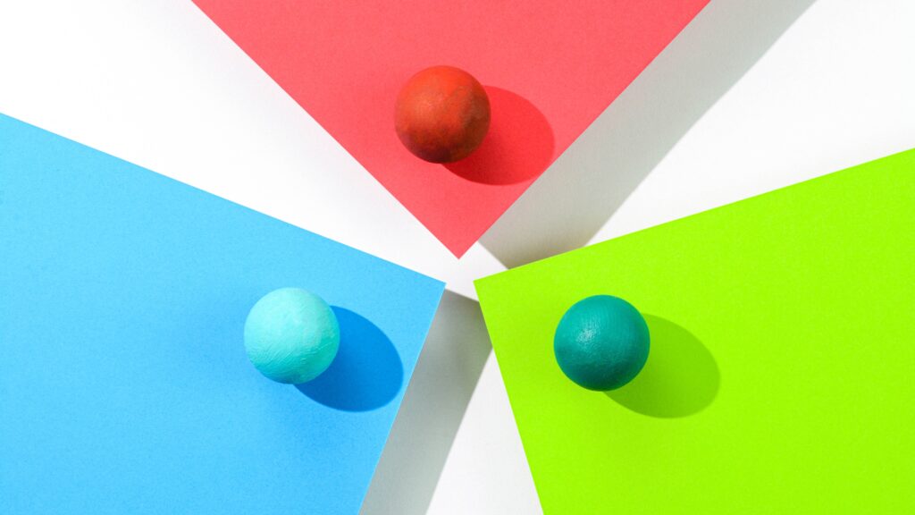 Three wooden spheres on the corners of separate cards in different colors.