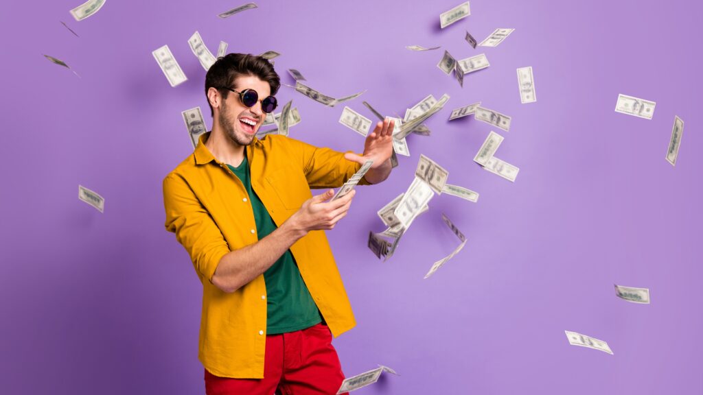 A young man celebrates as he throws money around.