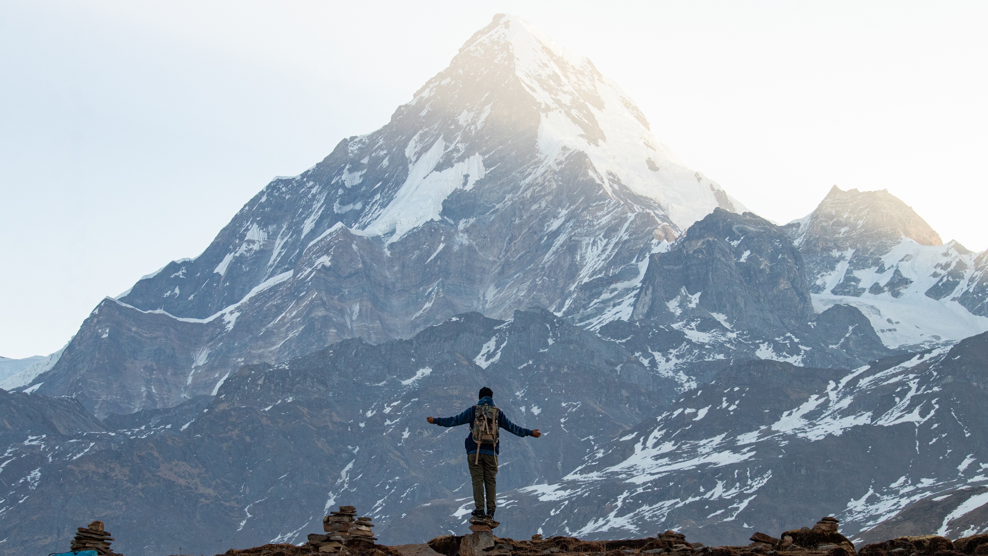 Un randonneur fait face au mont Everest, les bras écartés.