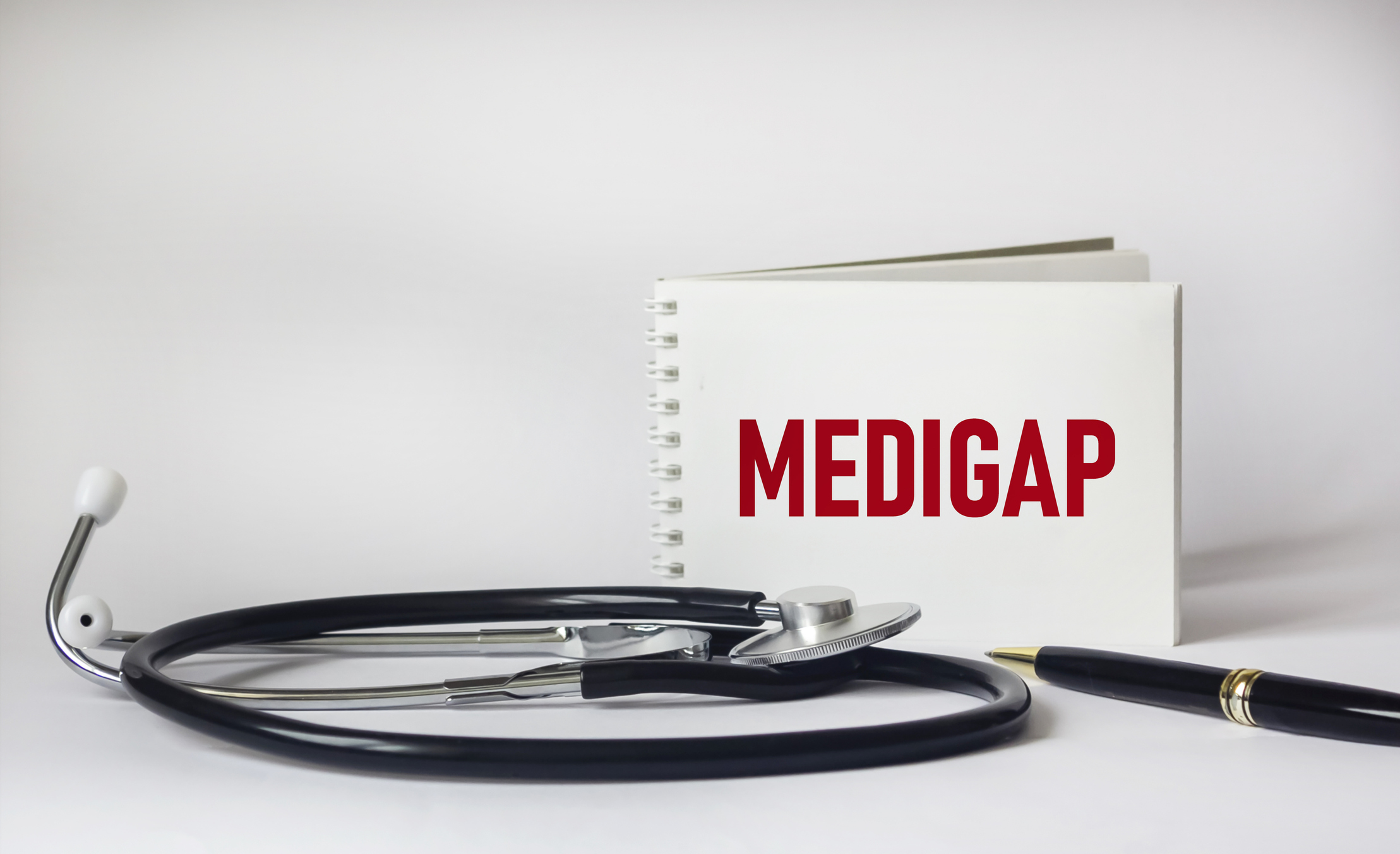 Mot Medigap sur le bloc-notes, le stéthoscope et le fond blanc