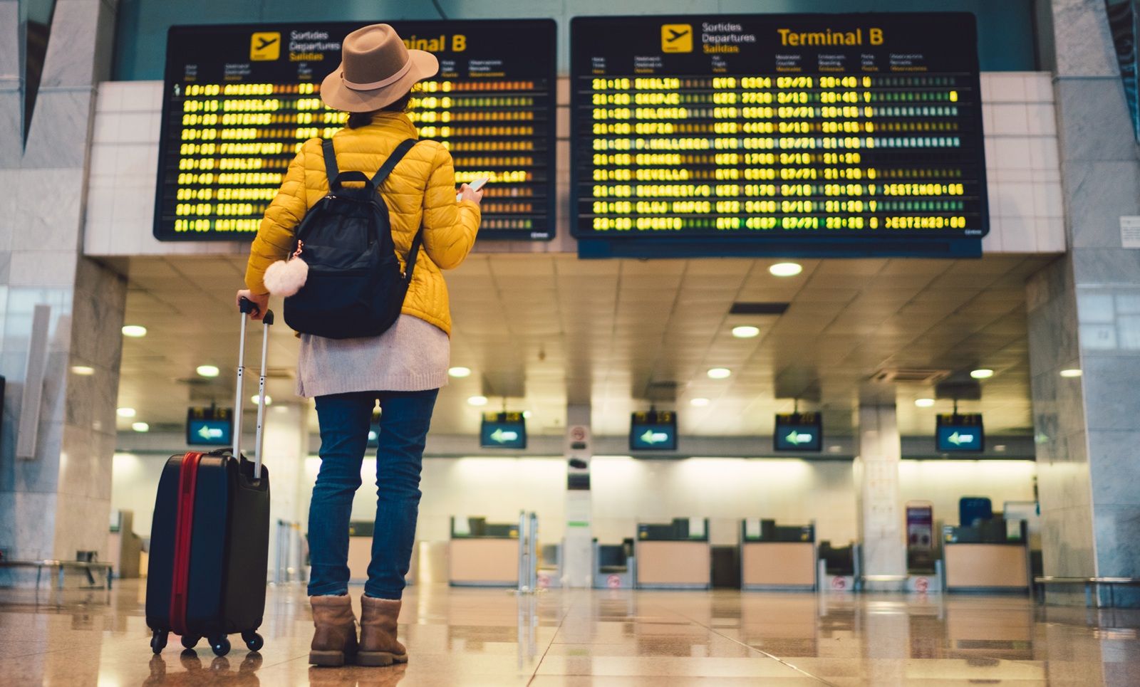 Young woman at the airport in Barcelona checking for the flight schedule