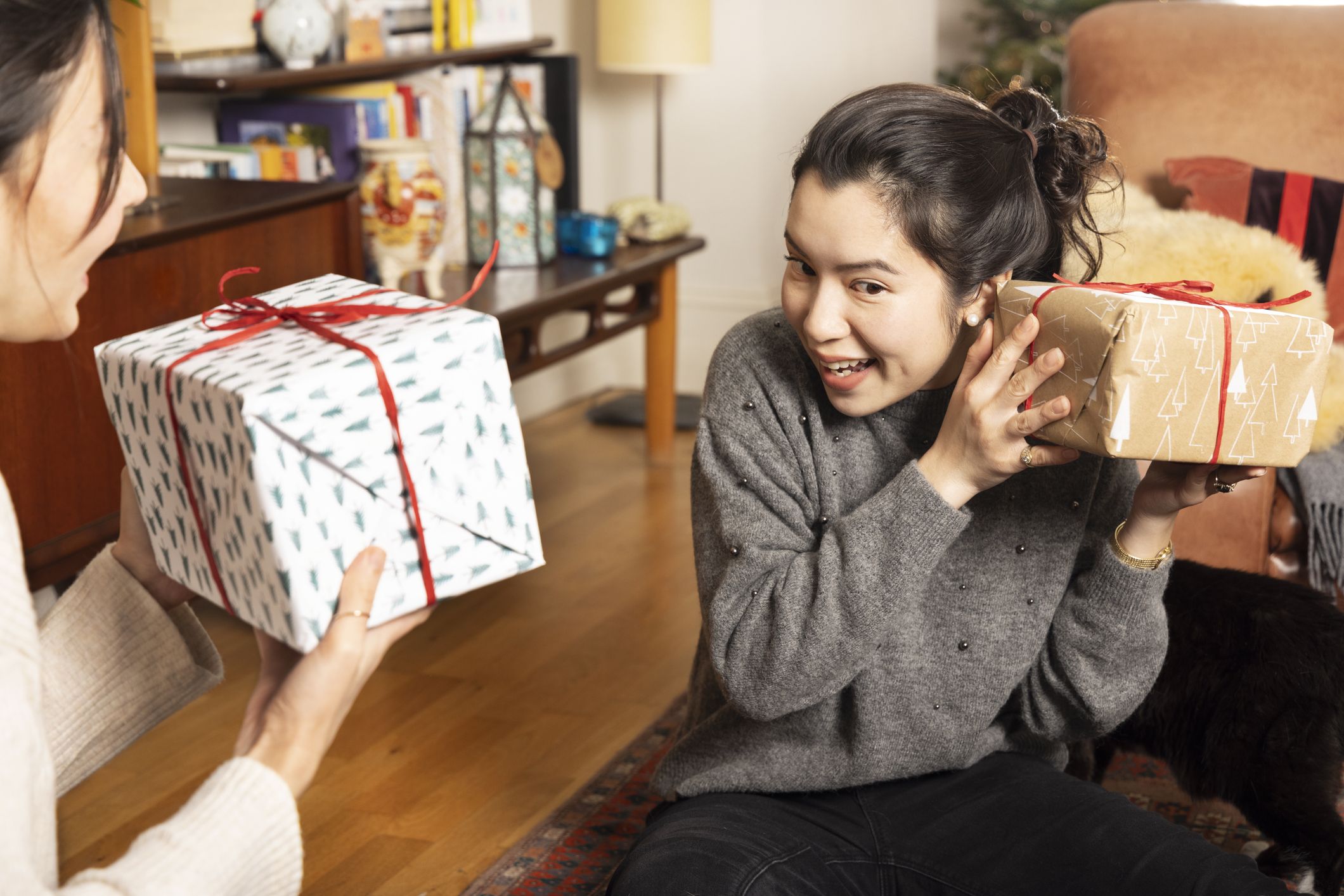 Une femme secoue le cadeau de Noël pour vérifier ce qu'il y a à l'intérieur.