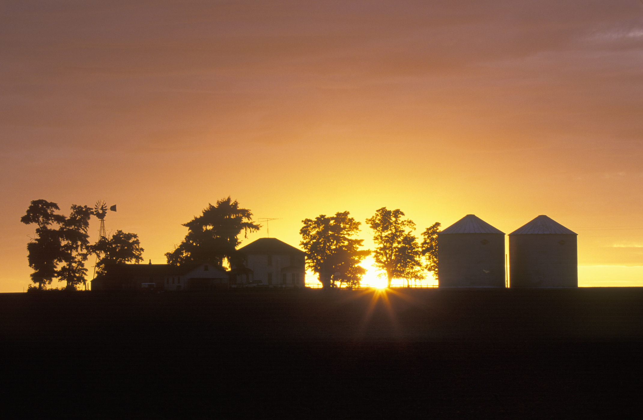 silhouette d'une ferme et de dépendances contre un coucher de soleil à Ritzville, Washington