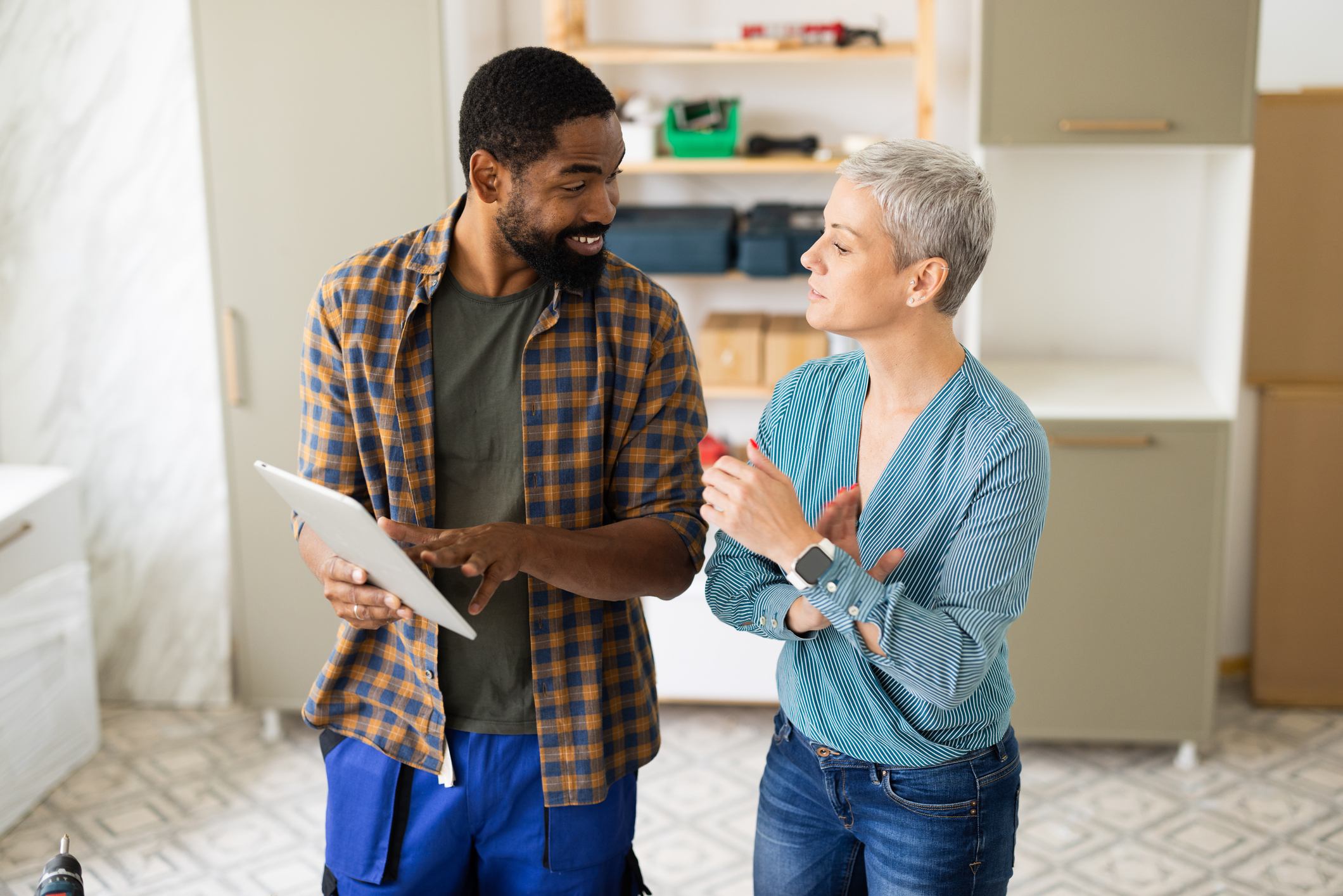 Entrepreneur montrant des informations sur une tablette numérique au client lors d'une rénovation domiciliaire