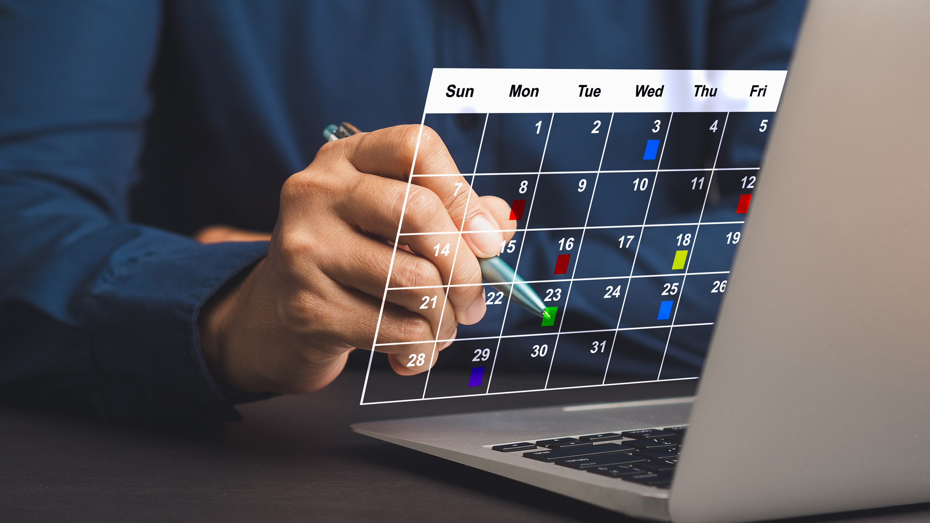 Un homme utilise un calendrier numérique qui semble flotter au-dessus du clavier de son ordinateur portable.