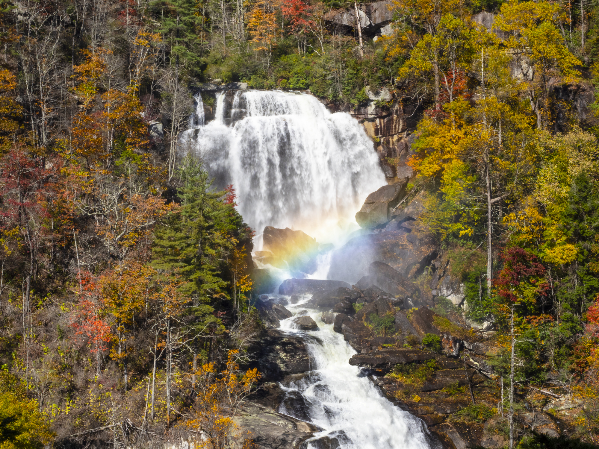 Whitewater Falls avec un arc-en-ciel s'étendant sur les rochers