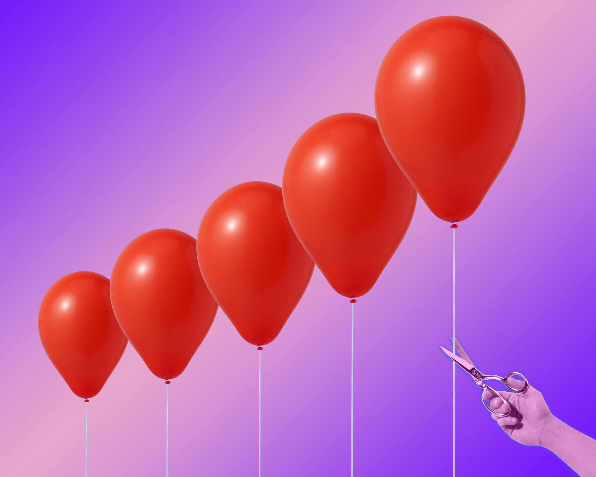 La main de l'homme avec des ciseaux en acier sur le point de couper la ficelle de l'un des 5 ballons à l'hélium rouge de différentes tailles, avec un fond violet dégradé