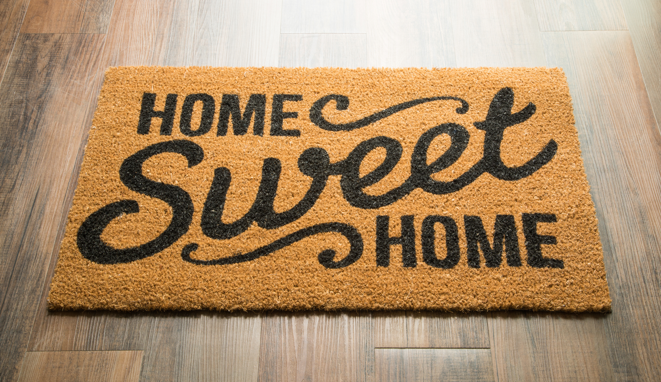 Tapis de bienvenue Home Sweet Home sur parquet.