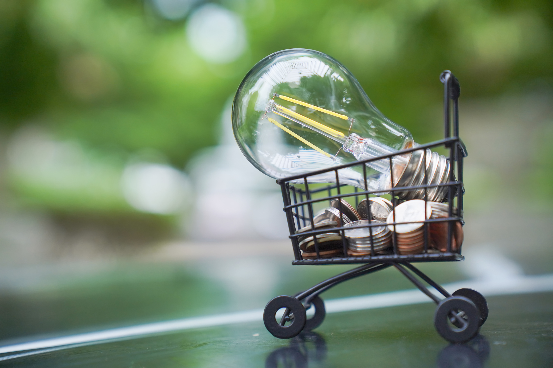 une ampoule posée sur une pile de pièces dans un panier indiquant des économies d'énergie