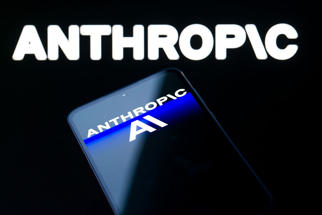 Le logo Anthropic AI est affiché sur un téléphone mobile avec la marque de l'entreprise visible en arrière-plan.