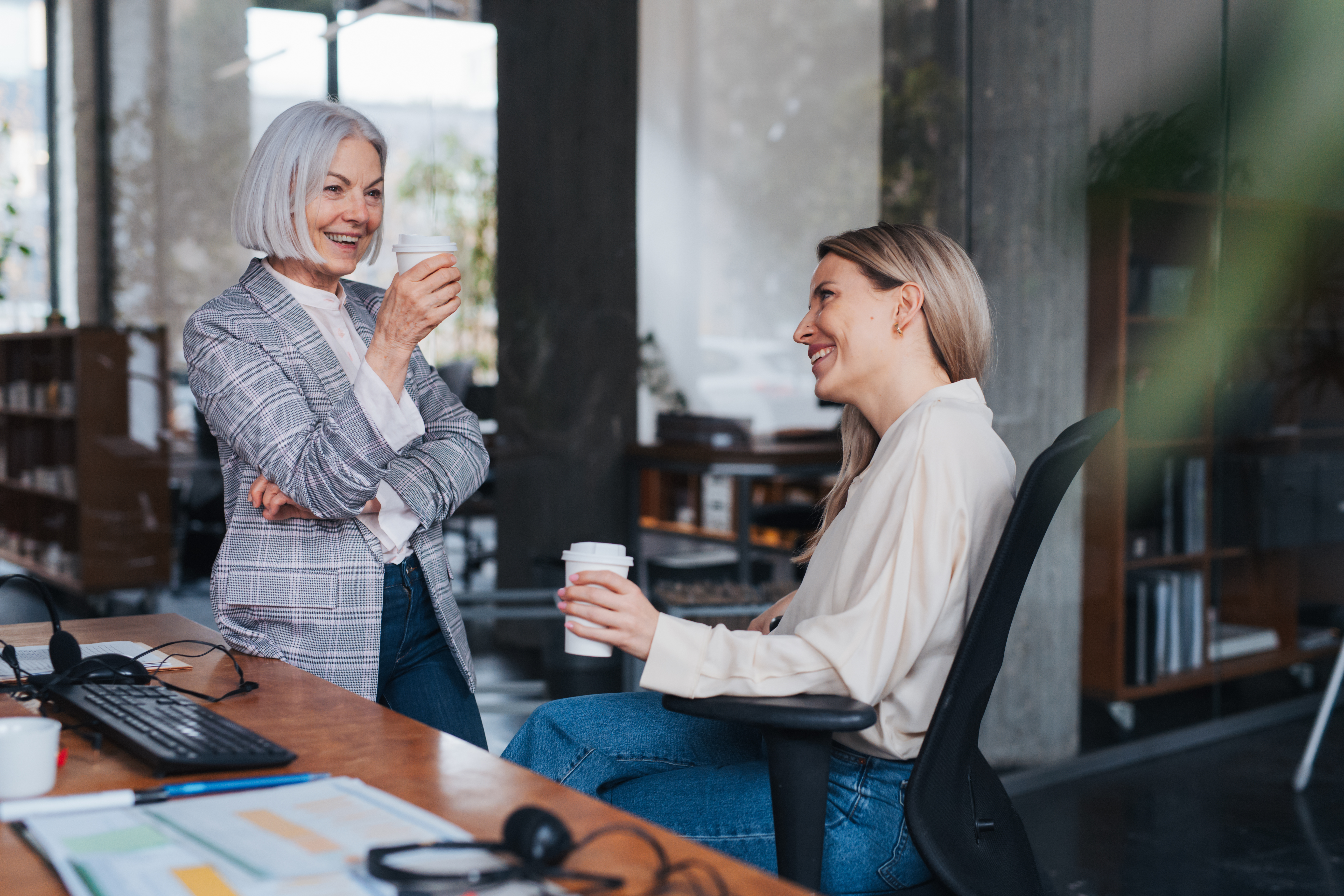 Courte pause pendant la journée de travail, café d'un collègue plus jeune. Amitié sur le lieu de travail entre collègues de différents groupes d'âge au bureau. Concept d'équipe diversifié selon l'âge.