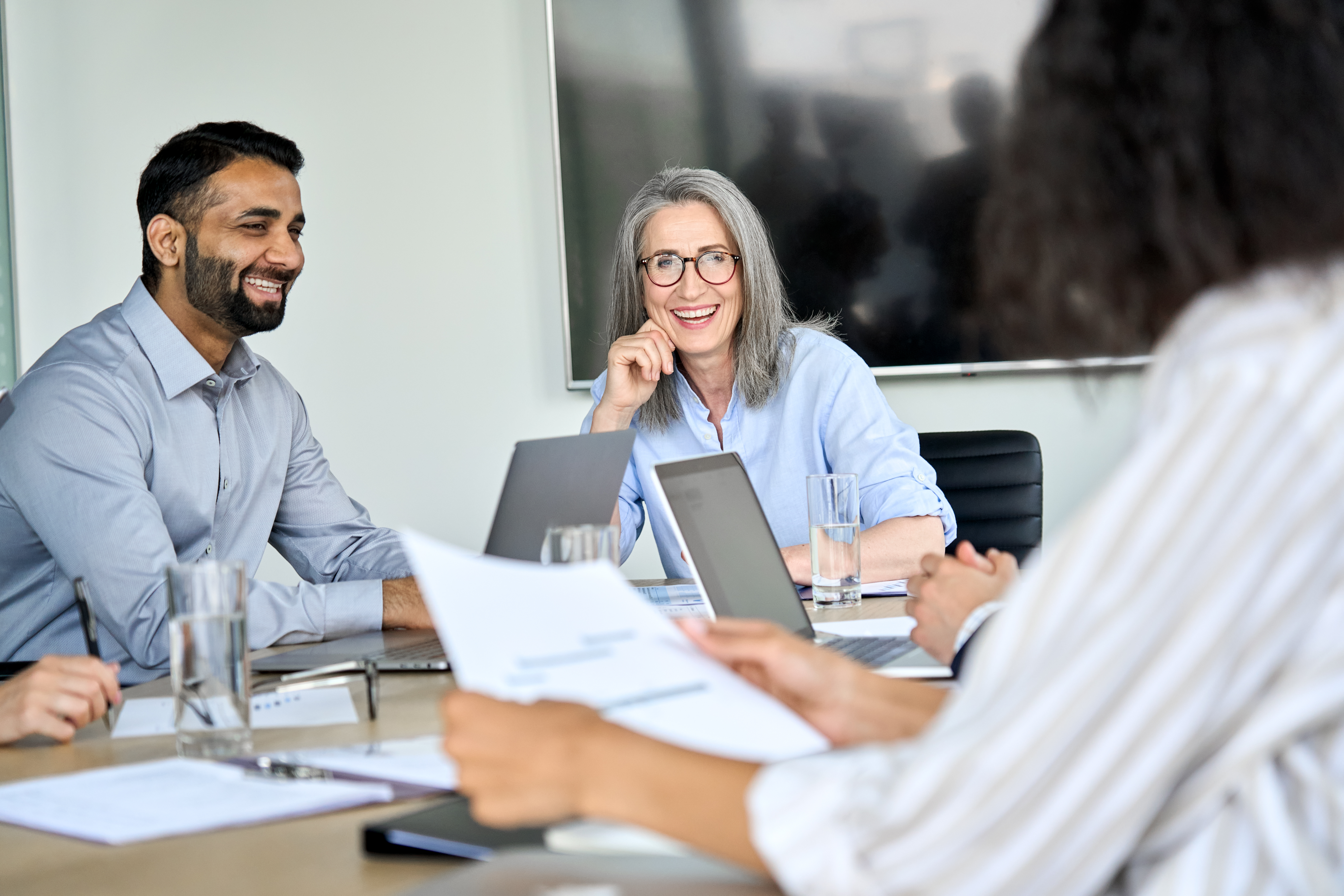 Une femme PDG senior et des hommes d'affaires multiculturels heureux discutant de la présentation de l'entreprise à la table du conseil d'administration. Équipe d'entreprise souriante et diversifiée travaillant ensemble dans un bureau de salle de réunion moderne.