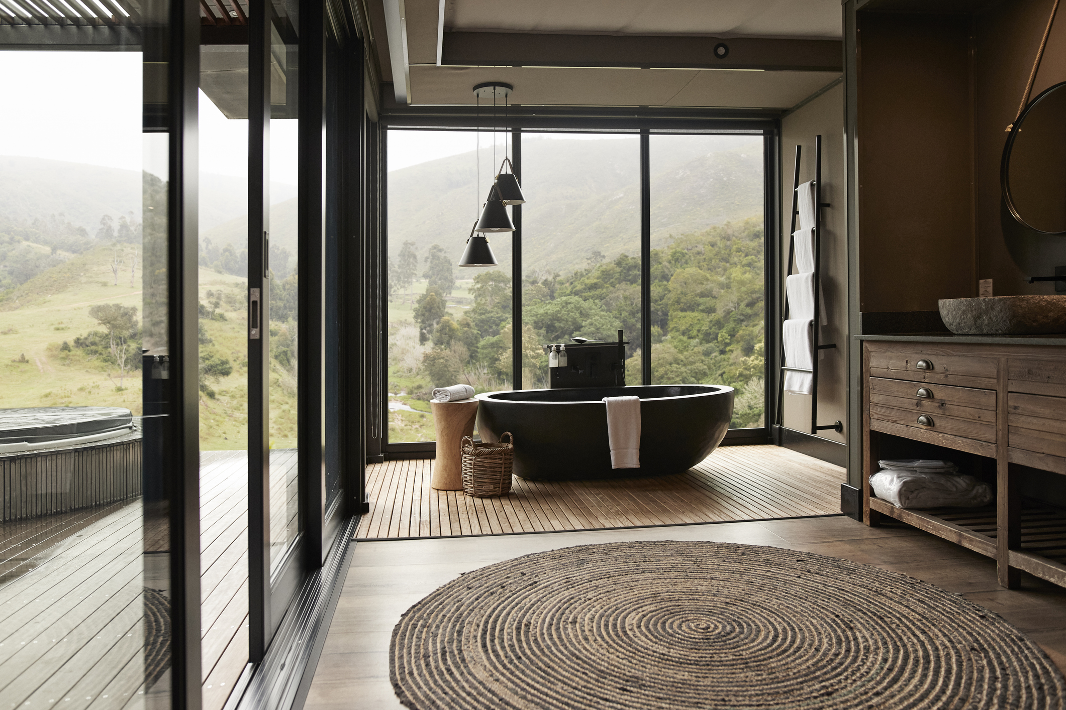 Suspension suspendue au-dessus d'une baignoire dans une salle de bain avec une grande fenêtre.