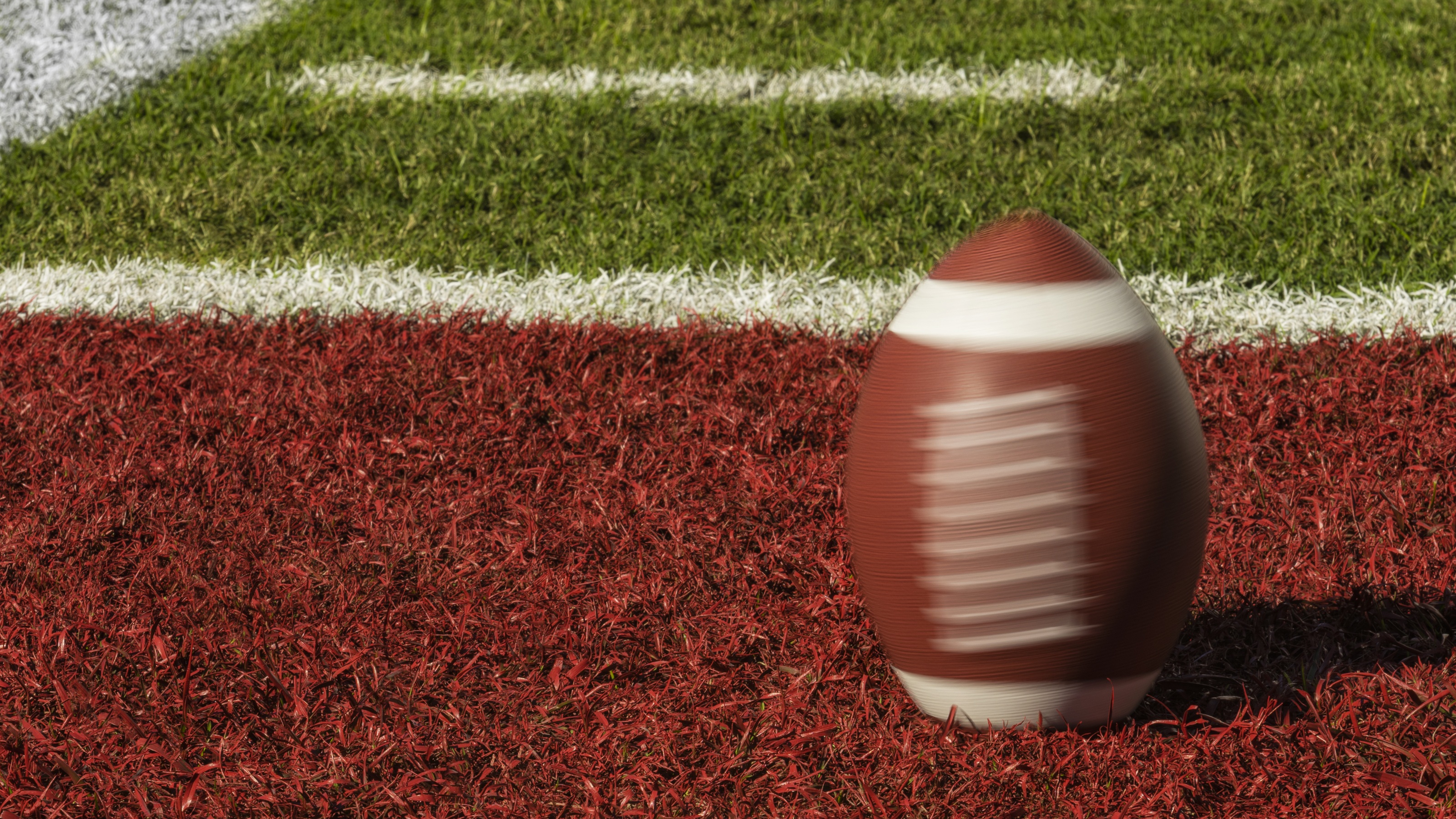 Un ballon de football tourne dans la zone rouge d'un terrain de football.