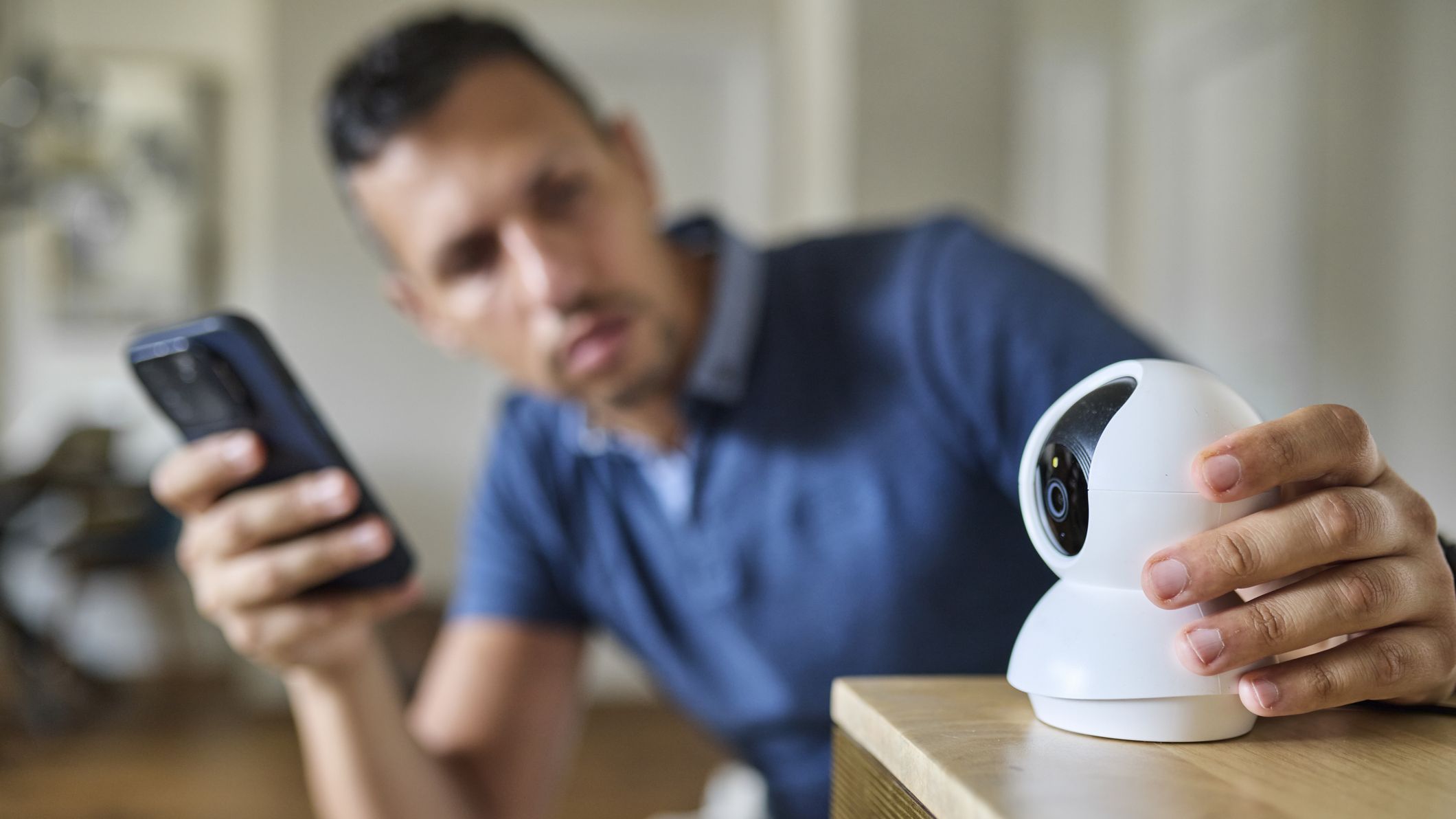 Homme configurant une webcam intelligente à l'aide d'un smartphone à la maison