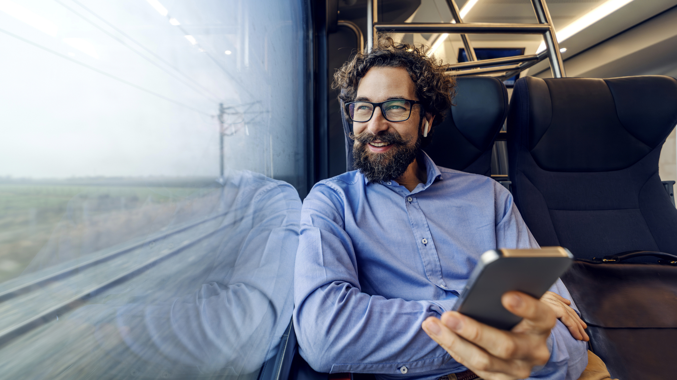 Un homme regarde par la fenêtre du train tout en écoutant de la musique.