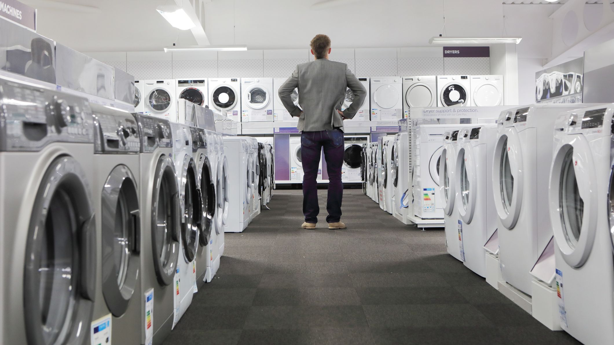 Homme regardant des machines à laver et des sèche-linge dans un magasin