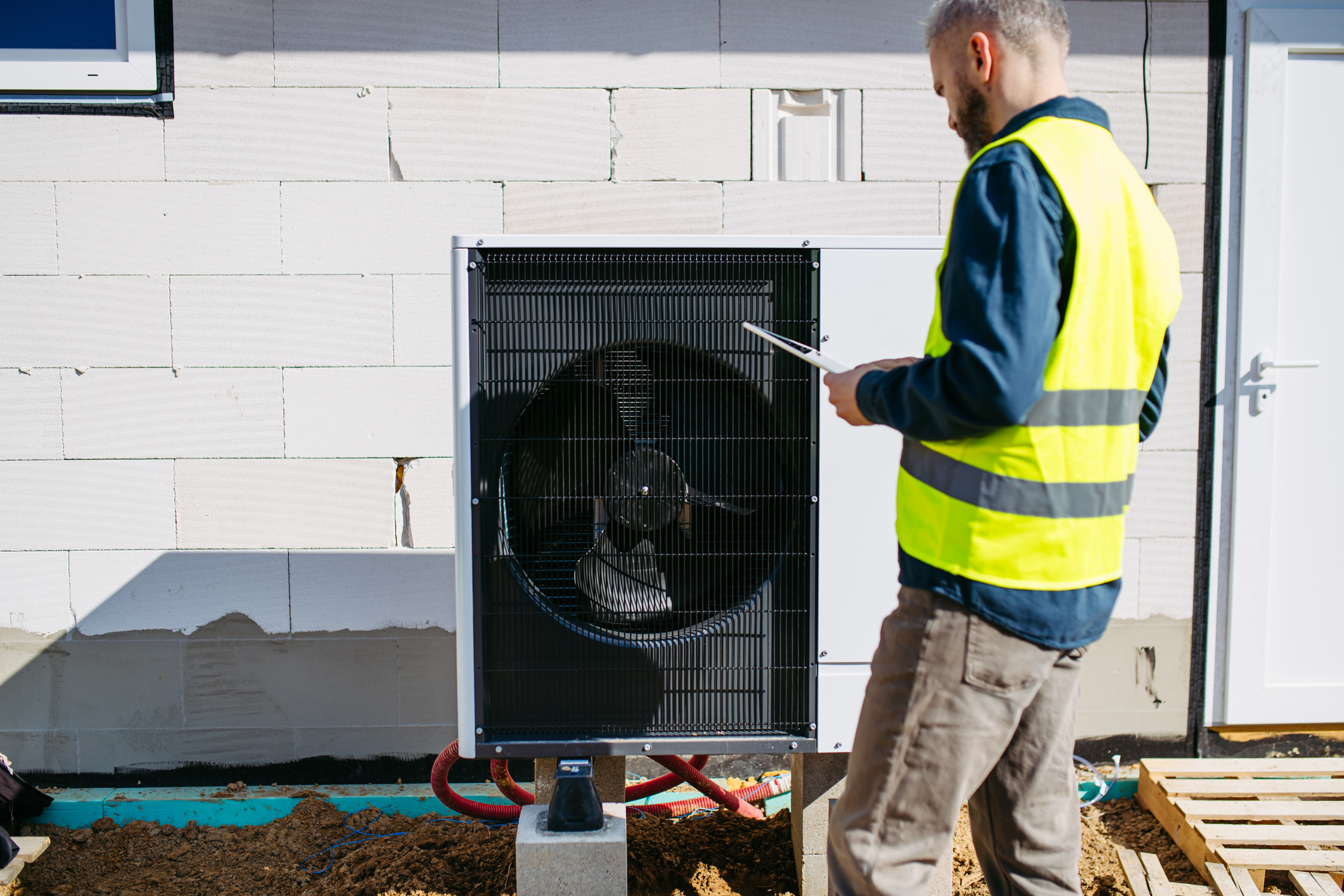 Technicien inspectant l'unité de pompe à chaleur extérieure pendant l'installation à domicile