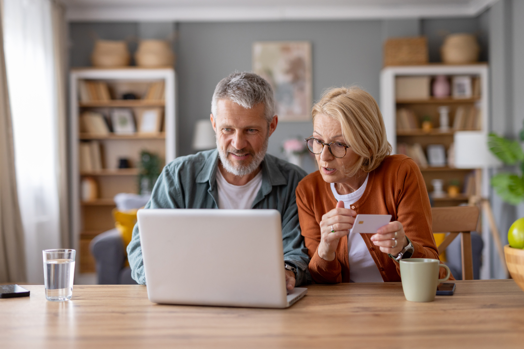 Un couple de personnes âgées chaleureux et engagés qui découvre le shopping en ligne et partage sa joie et sa curiosité quant à l'achat de produits à la maison.