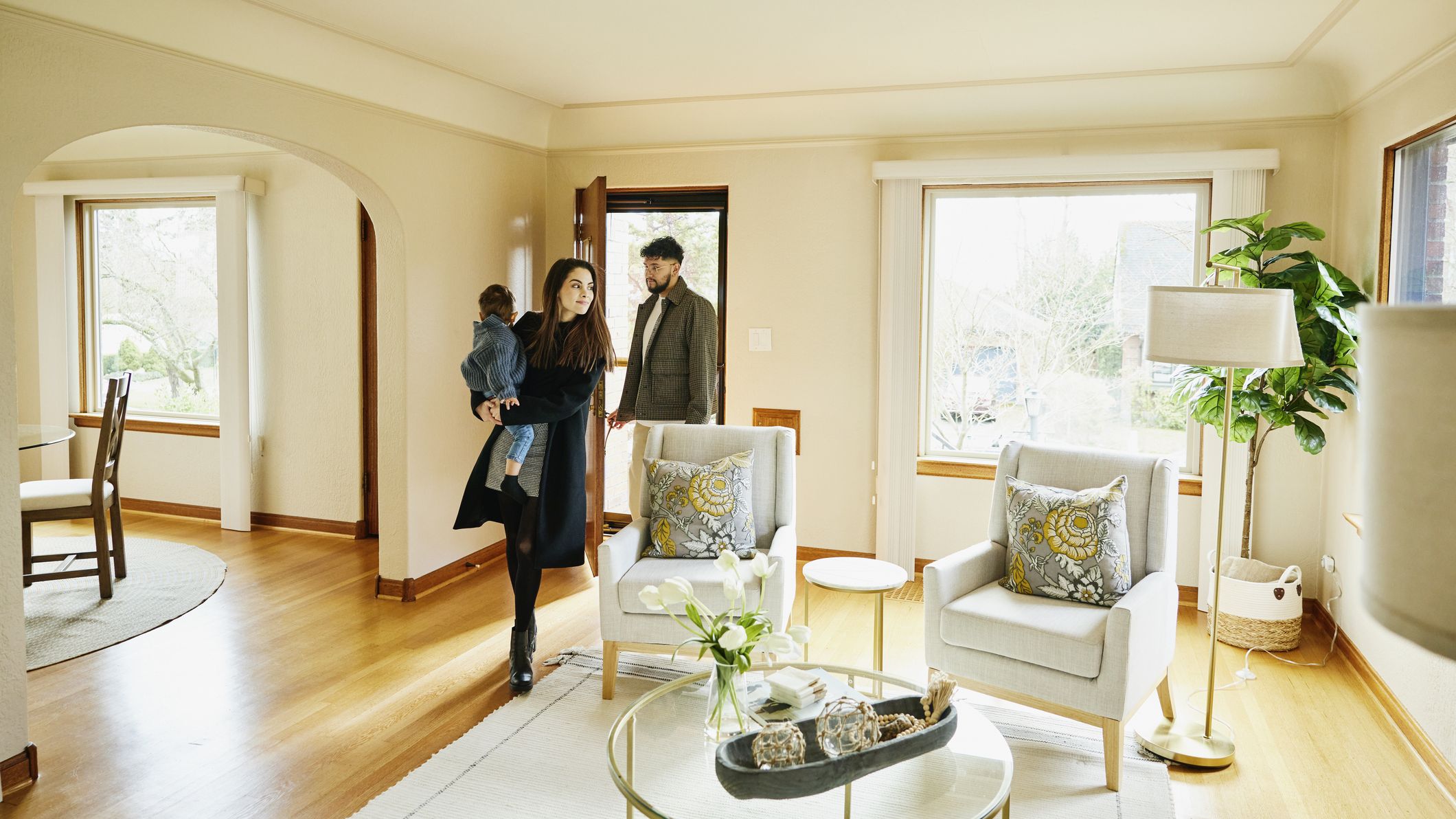 Plan large d'une famille avec un enfant en bas âge marchant par la porte d'entrée dans le salon de la maison à vendre pendant la journée portes ouvertes