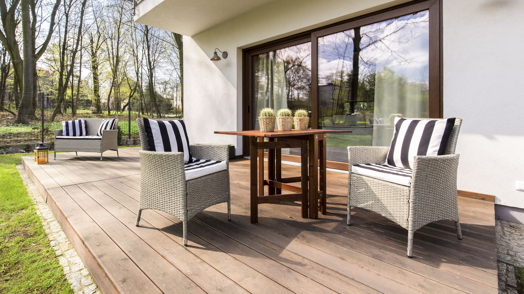 Grand porche confortable en bois avec chaises et table basse à l'arrière d'une grande résidence