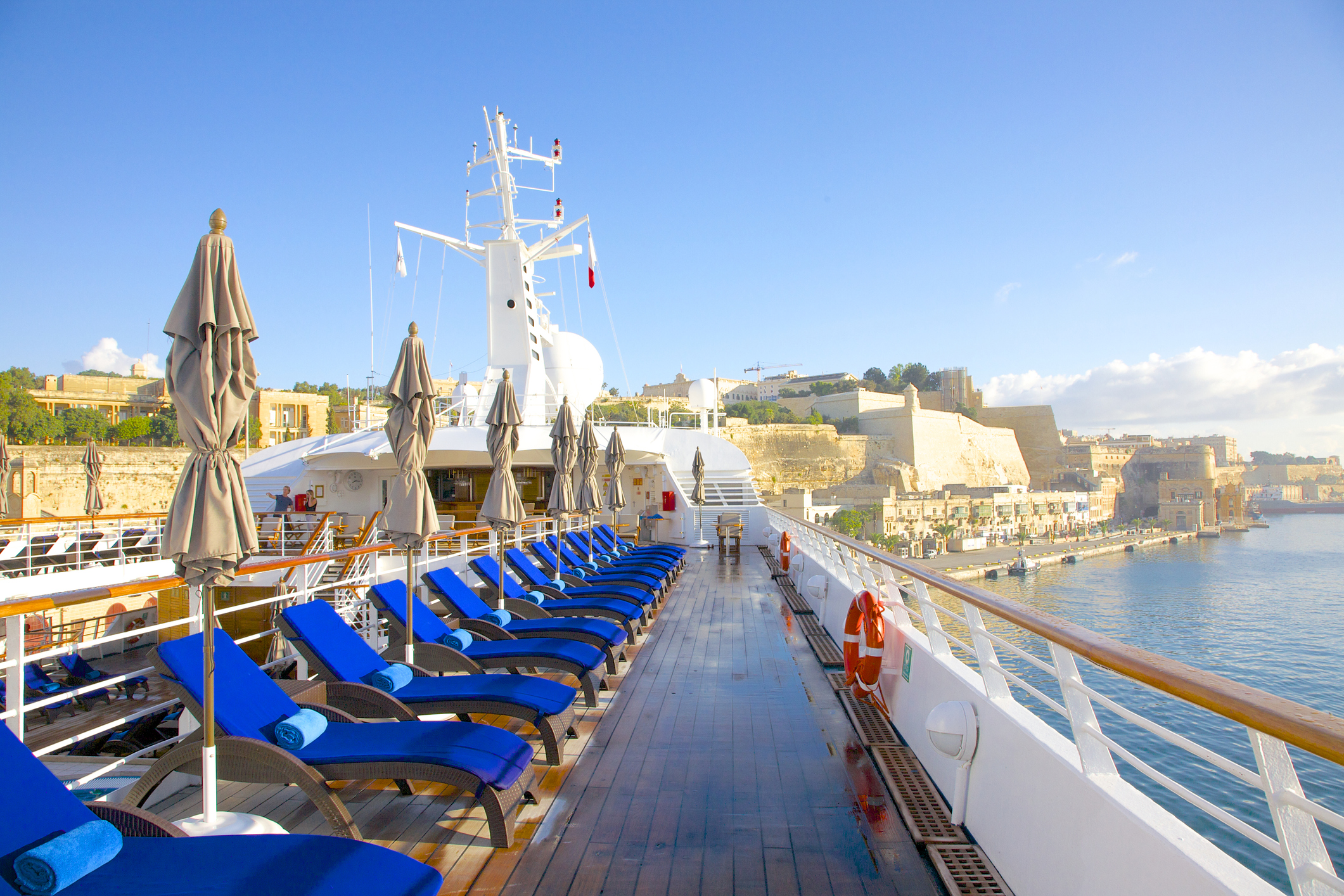 Soleil matinal sur le pont en teck et coussins bleu royal attendant les passagers du yacht Windstar Star Legend. Le yacht est amarré près d'anciens murs de fortification à La Valette, à Malte.