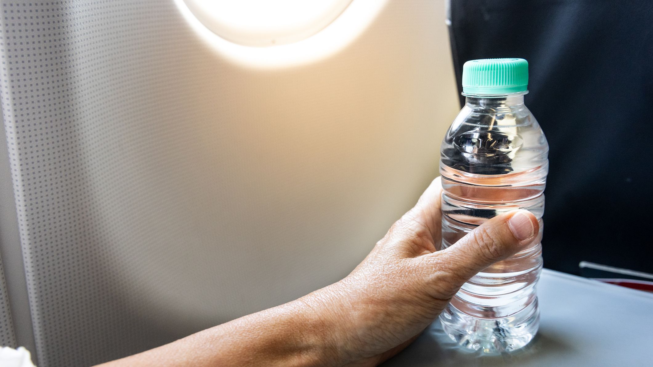 Une main tenant une bouteille d'eau sur une table de plateau d'avion