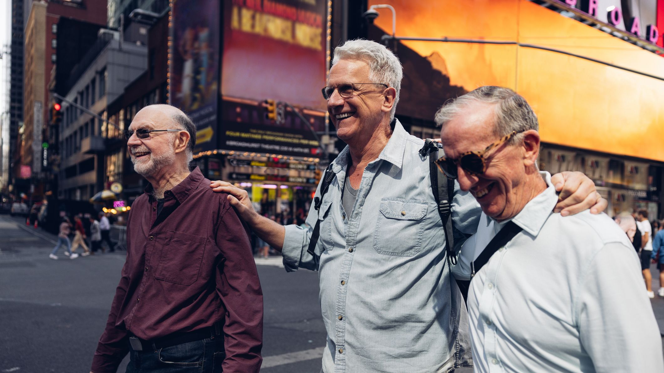 Trois amis matures regardant autour de Times Square à New York. Ils marchent dans les rues bondées de Manhattan