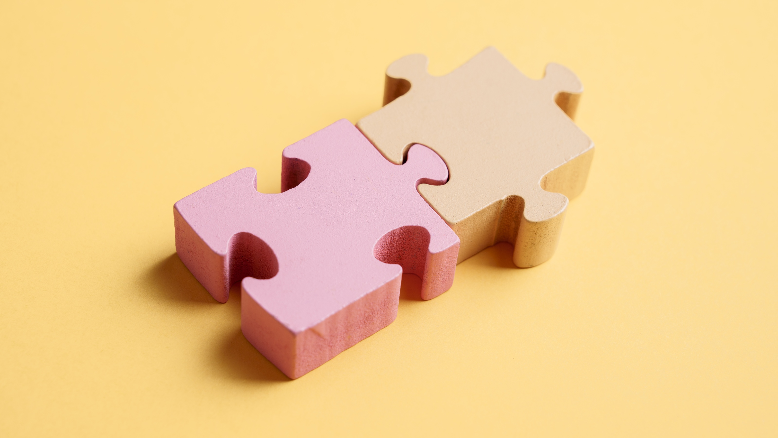 Deux pièces de puzzle pastel s'assemblent sur un fond jaune.