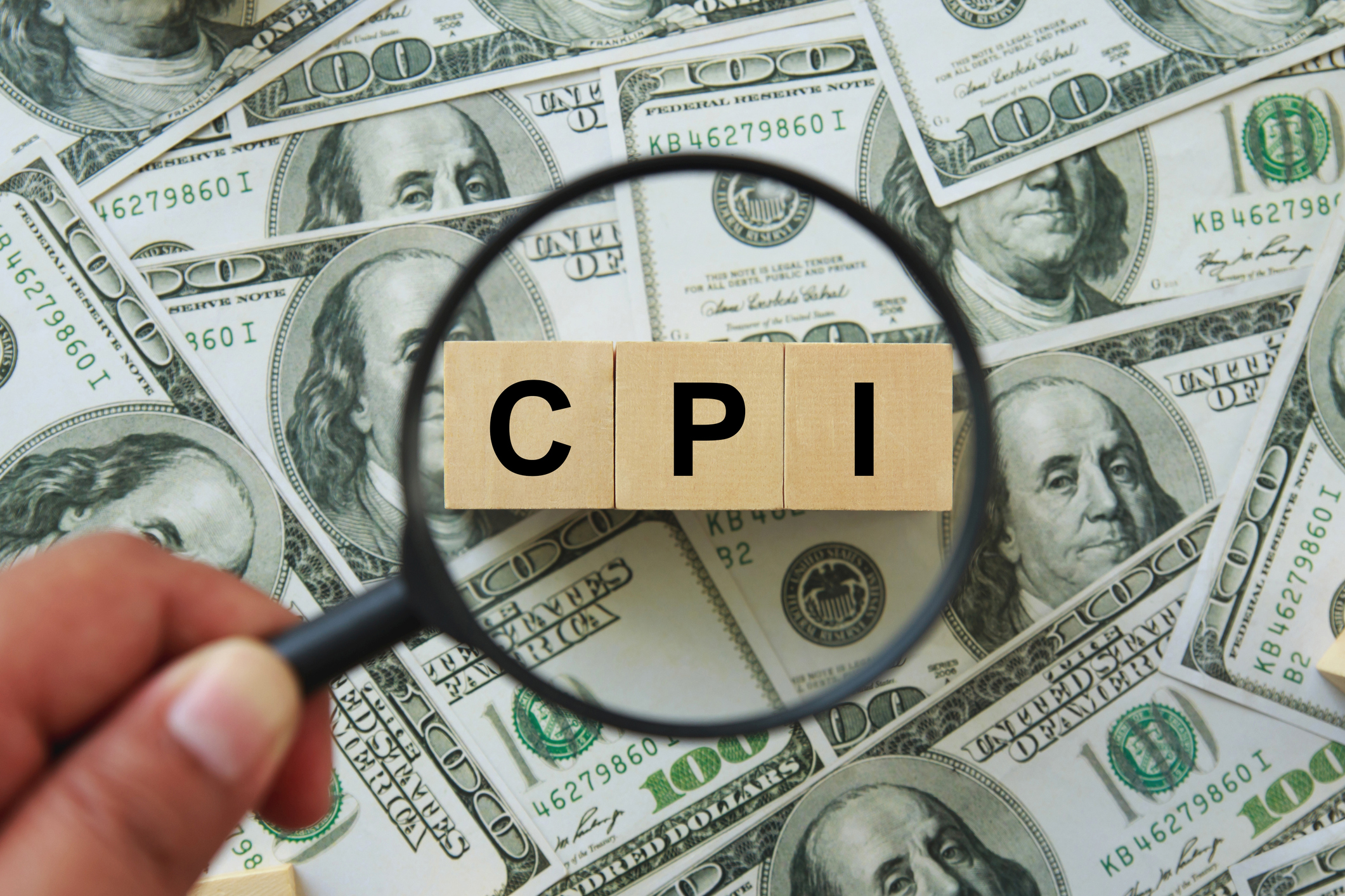 IPC, symbole de l'indice des prix à la consommation. main tenant une loupe enquêtant sur un bloc de bois avec les mots CPI, indice des prix à la consommation sur les billets d'un dollar. Entreprises et IPC, concept d'indice des prix à la consommation.