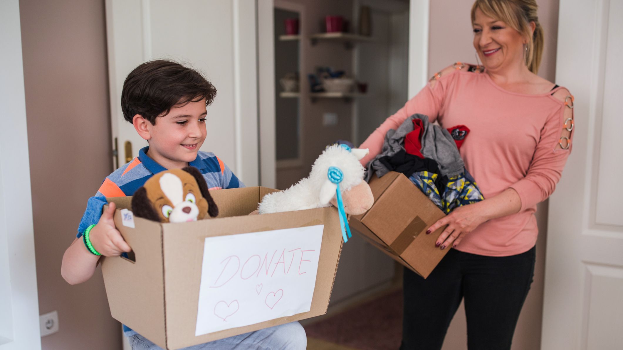 Femme heureuse et son fils tenant tous deux des boîtes pleines de choses à faire un don