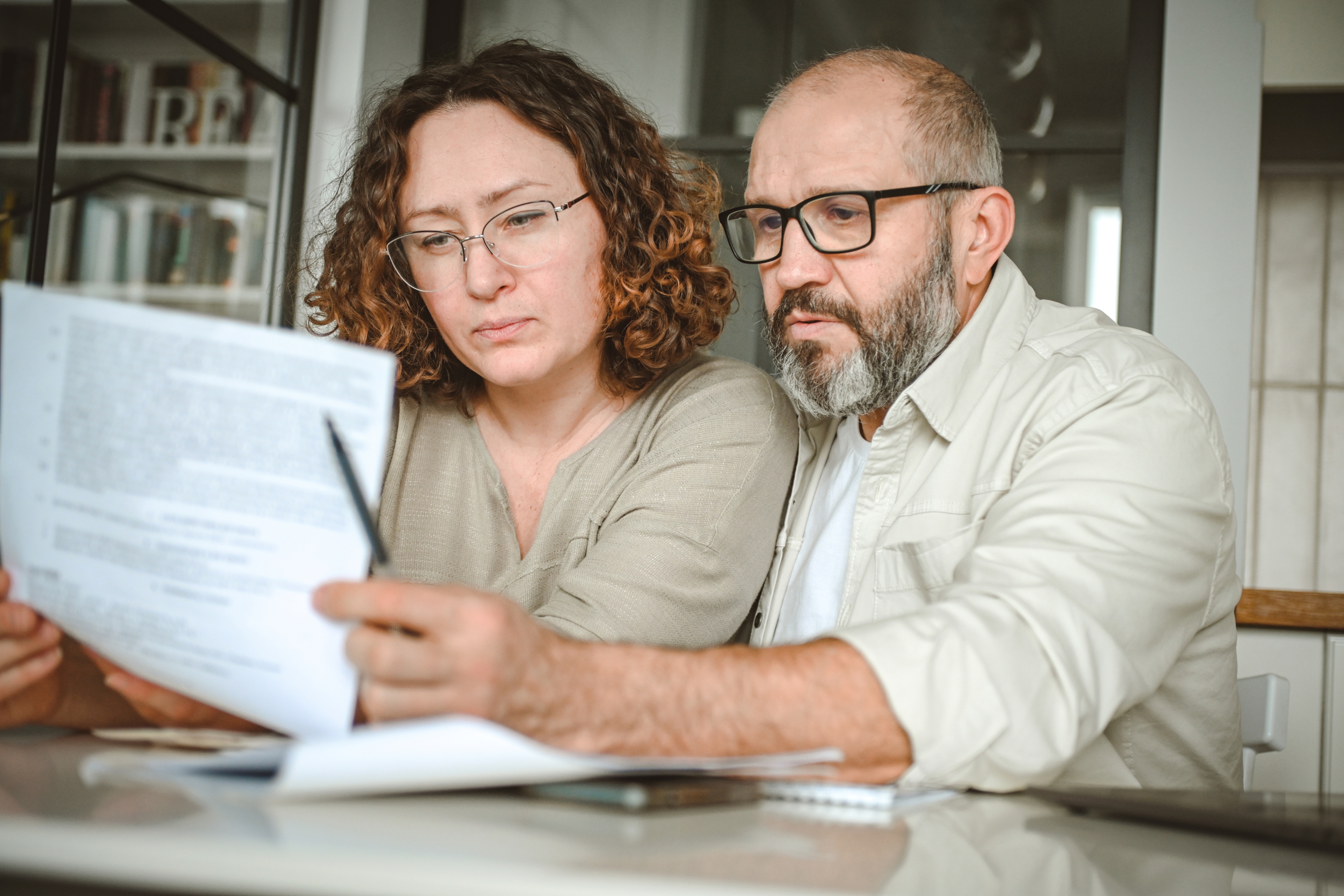Un couple d'âge mûr examine des documents alors qu'il est assis à leur table à manger.